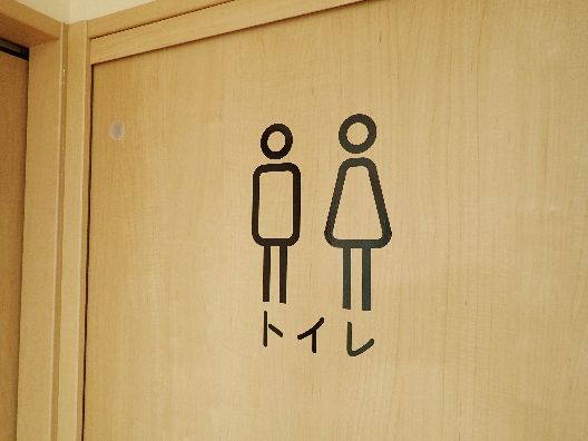 木製のドアには「トイレ」と書かれ、男女のシルエットのイラストが描かれている。