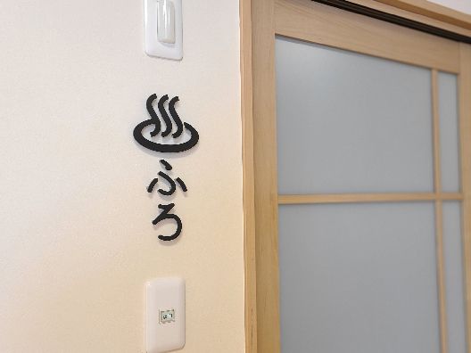 白い壁には「ふろ」と書かれ、温泉マークが描かれている。その横にはドアが付いている。