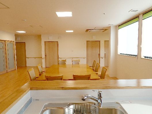 対面式キッチンから食堂を見た様子。大きなダイニングテーブルセットが置かれている。