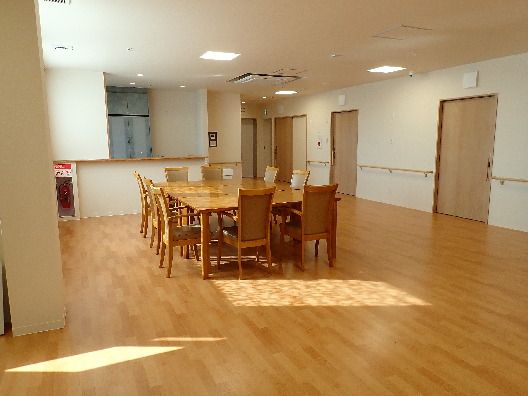 木製の大きなダイニングテーブルセットが置かれた食堂。その周りには居室のドアが設置されている。