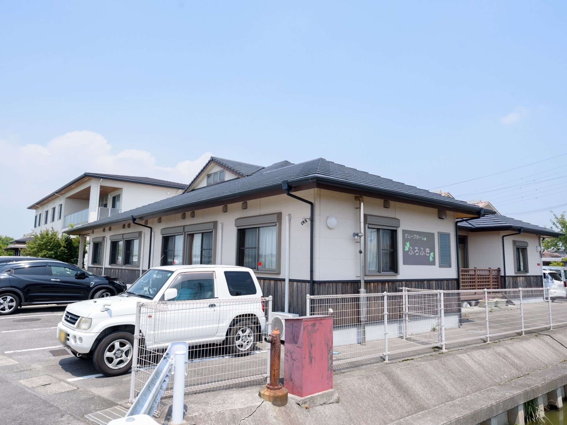 落ち着いた色調の中に木の温かみを感じる、一軒家のような外観。入口へ続くスロープや駐車スペースも整備されており出入りしやすい。