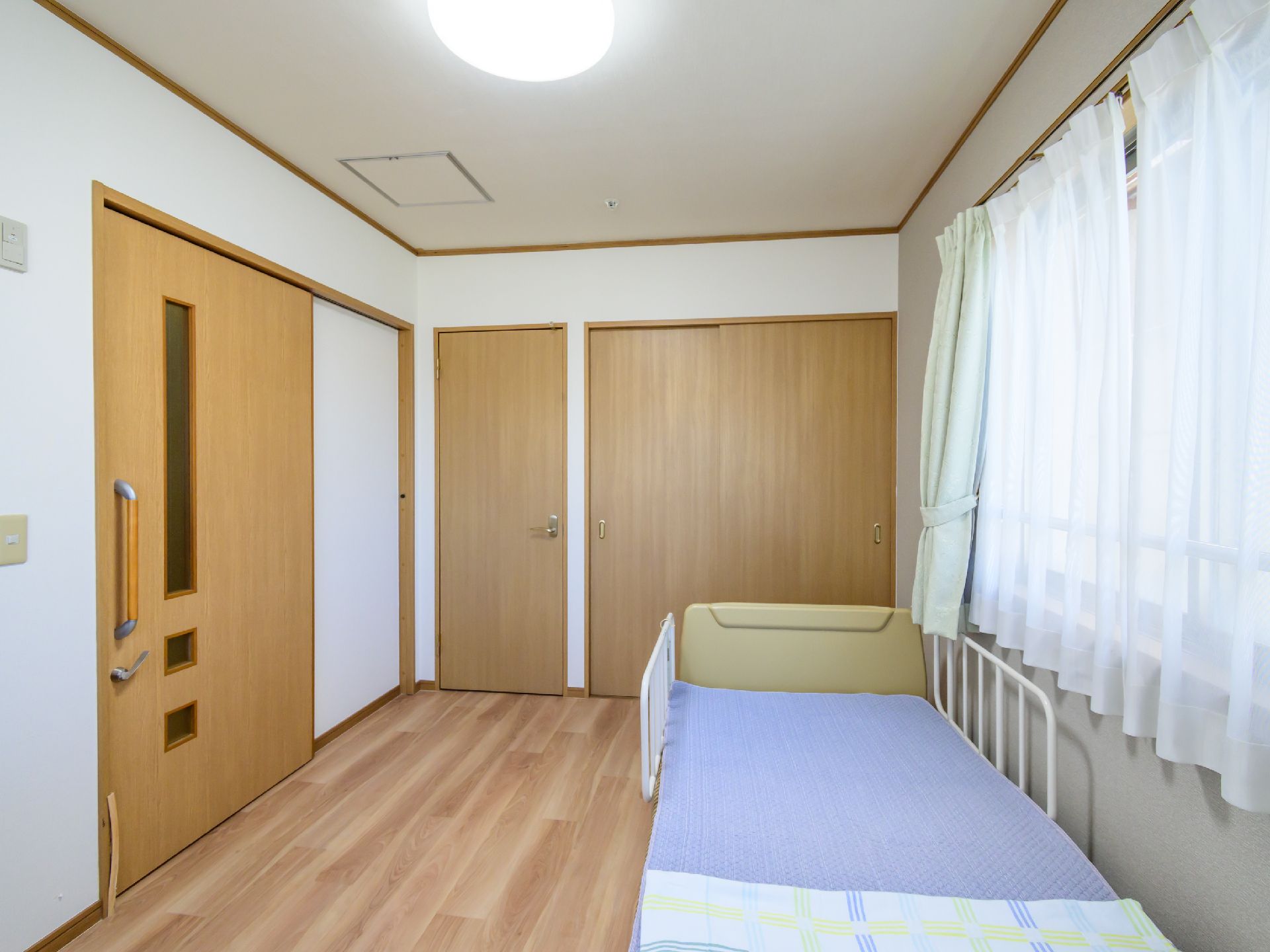 大きな窓が設置され、大きな介護ベッドが置かれている居室