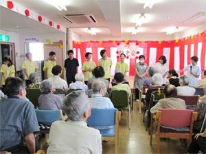 敬老会の日のスタッフによる挨拶。一列に並んだスタッフを入居者も見ている。