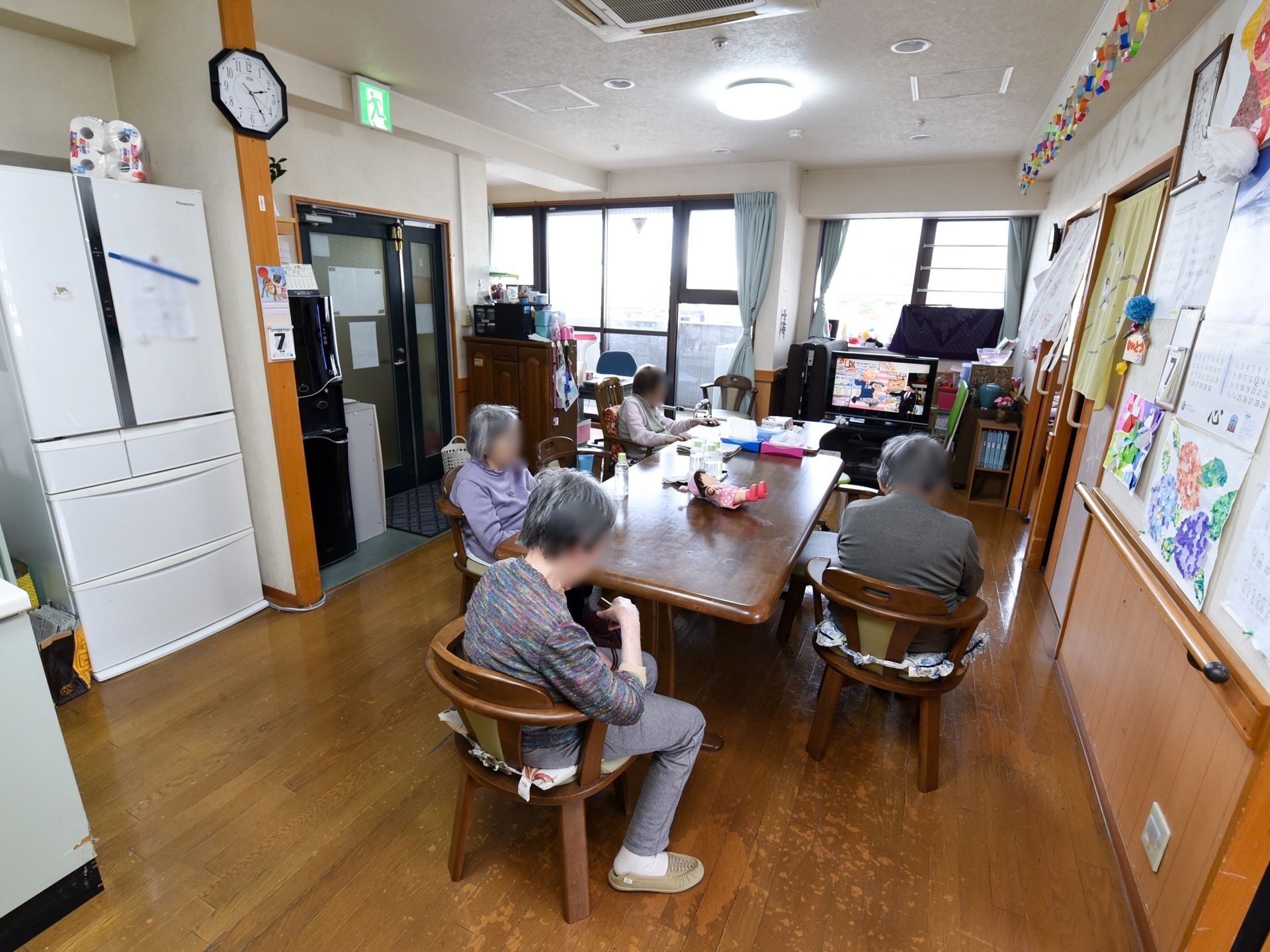 広い共有スペースの奥は一面窓になっている。奥に大型液晶テレビが置かれている。手前には冷蔵庫が用意されている。