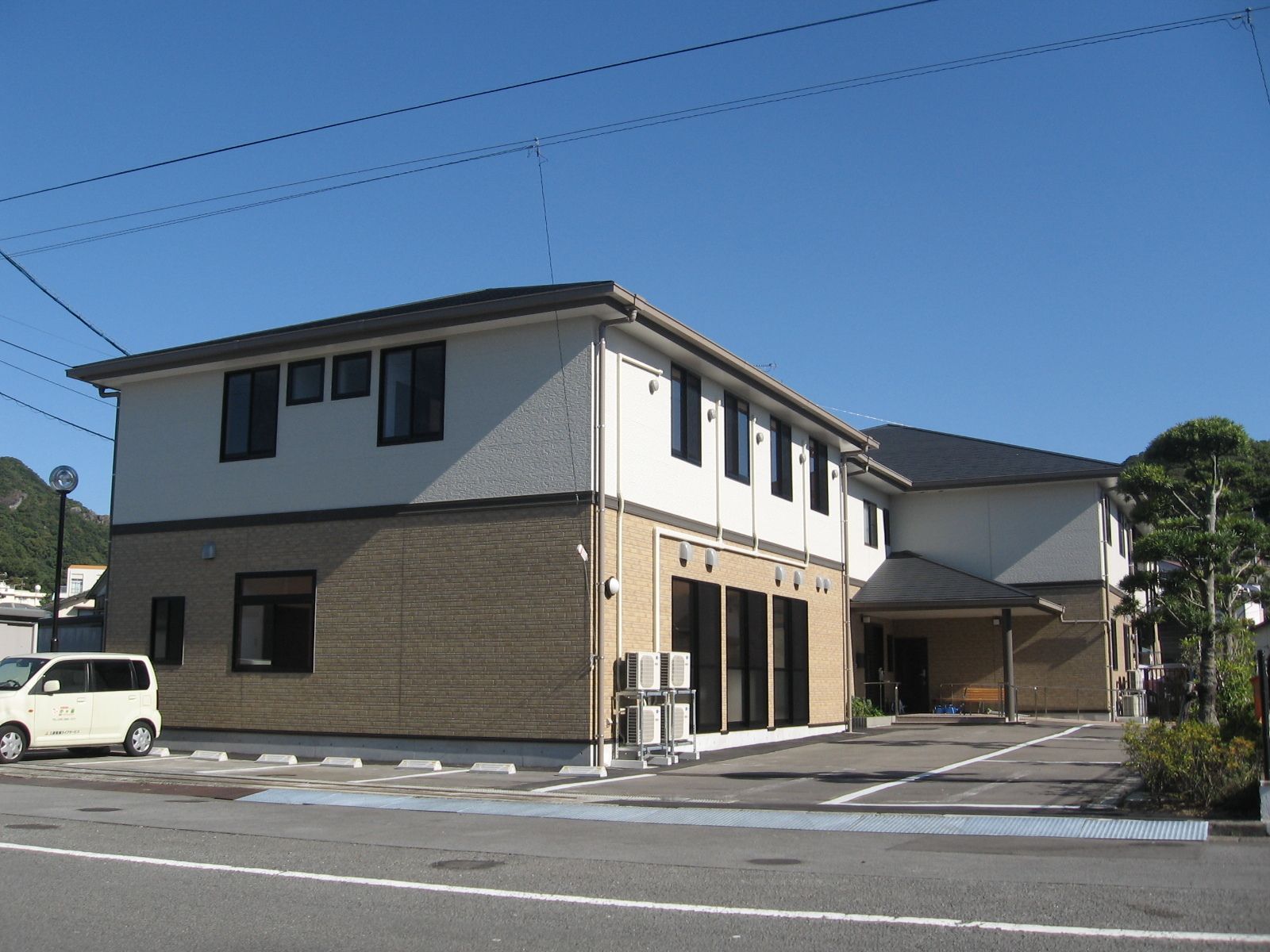 ベージュと白の2階建ての建物。屋根にはスロープと屋根も設置されている。