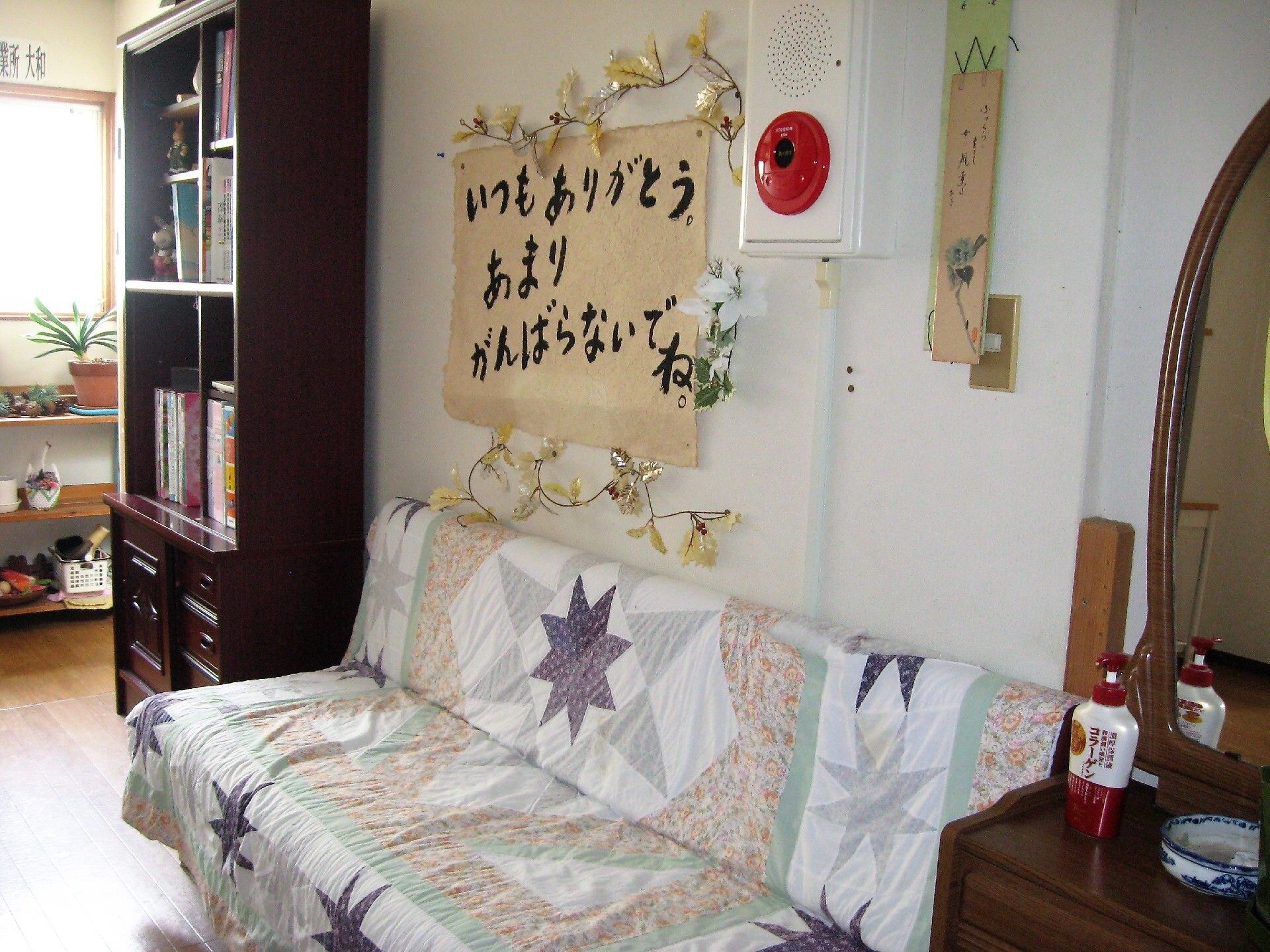 パッチワークのカバーが掛かったソファーや本棚が設置された共有スペース