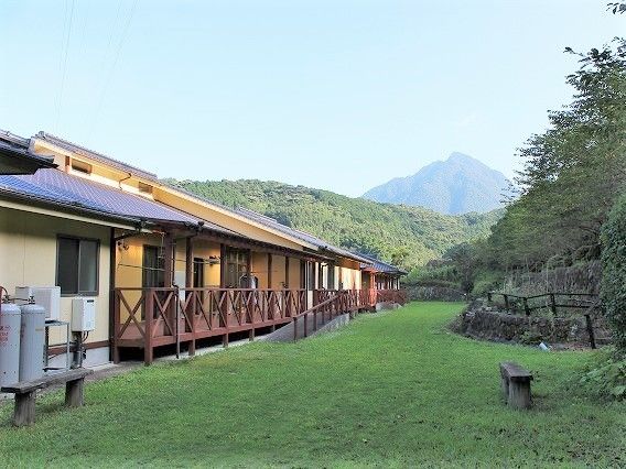 ウッドデッキが付いた平屋建ての建物。敷地が広く、緑にあふれる環境。