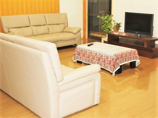 大きなソファが二つ、テレビを囲むようにして置かれ、テーブルの上には布がかけられている。