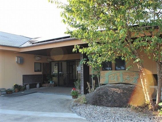 玄関先にはたくさんの花のポットが置かれ、大きな木が植えられている。