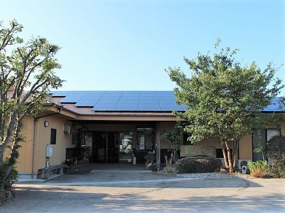 木造平屋建ての建物の両サイドに木が植えられ、影を作っている。