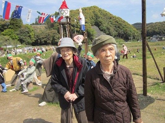 あちこちにいろいろなポーズをしたかかしたちが飾られていて、入居者は帽子をかぶりそれを見物している。