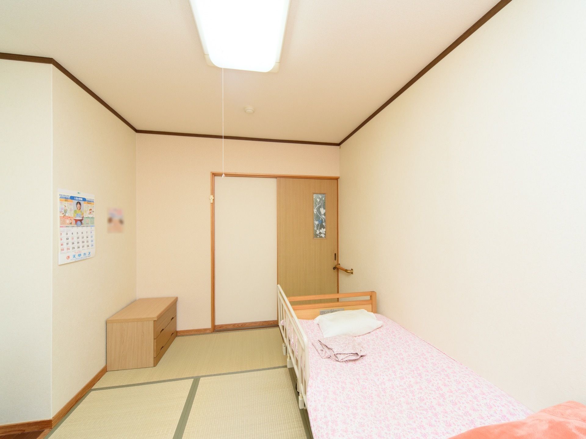 畳敷きの和風タイプの居室である。介護用ベッドが置かれ、カウンター付きの整理棚が壁際に設置されている。