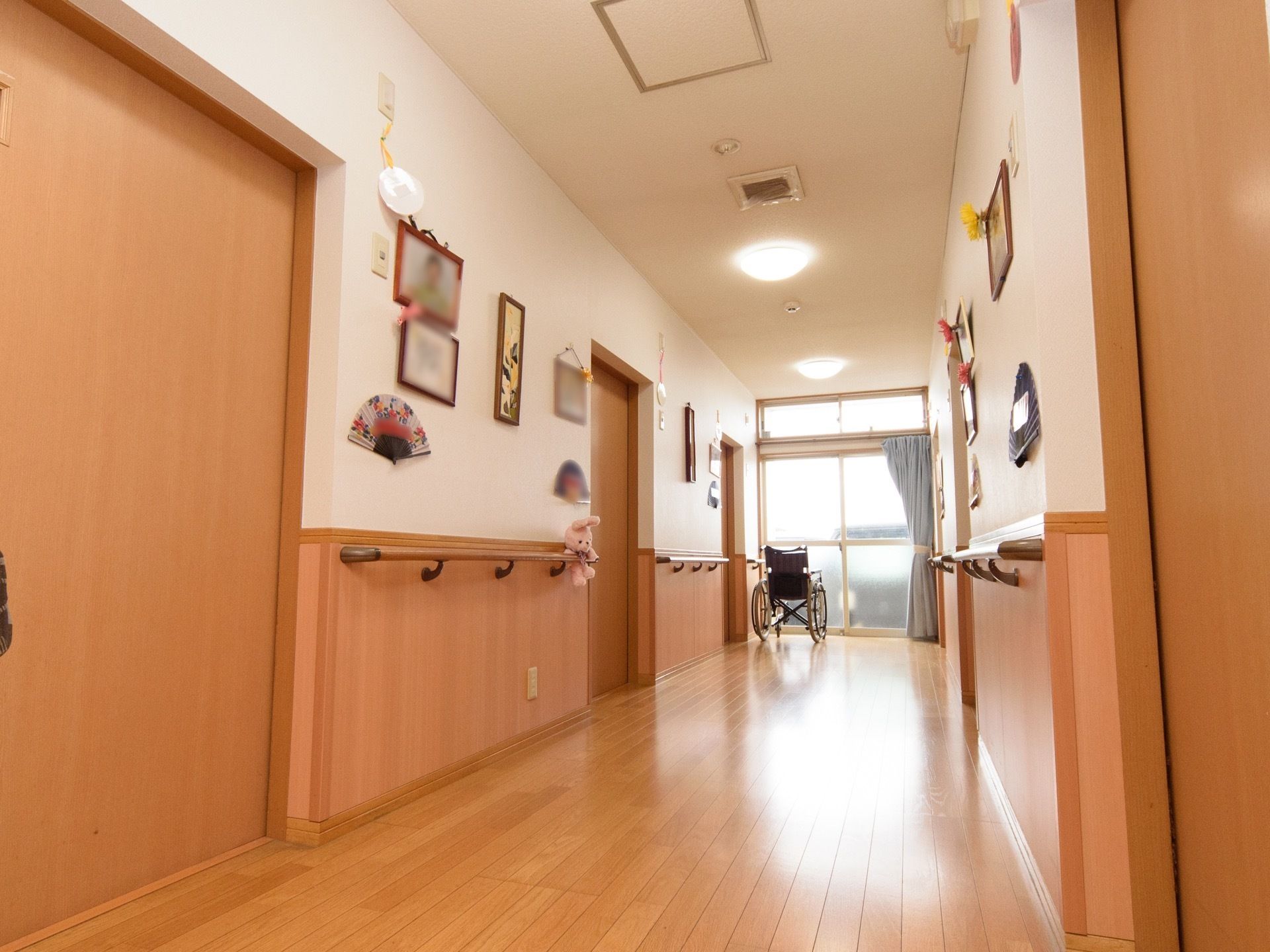 通路の奥にガラス張りのドアが設置され、日差しが差し込んでいる。壁には、額縁に入ったさまざまな作品が飾られている。