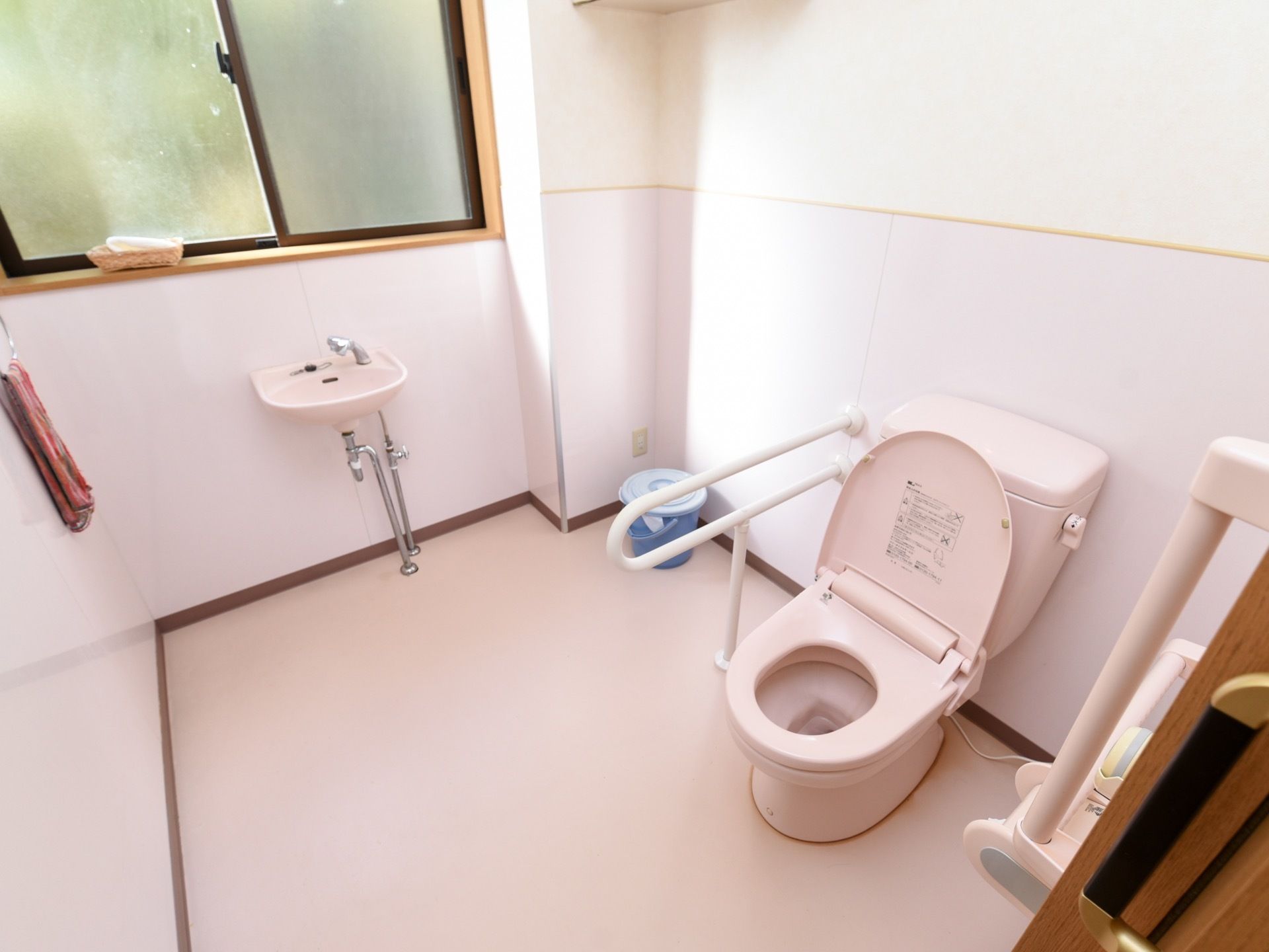 トイレは個室内の面積がとても広く作られている。奥に窓があり、かごに入れられたタオルが置かれている。窓の下に流し台がある。