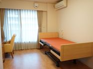 居室は窓やエアコンが完備されている。昇降式の介護用ベッドが設置され、壁には呼び出しブザーが設置されている。