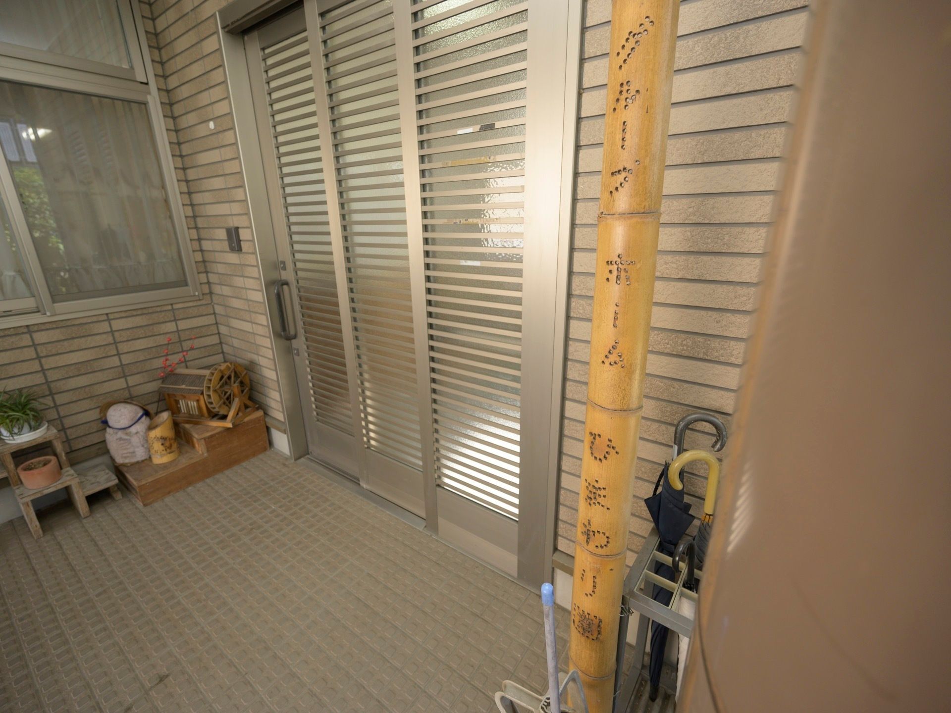 玄関は間口の広いスライド式が採用されており、横にはインターホンが設置されている。横には、傘立てが置かれている。