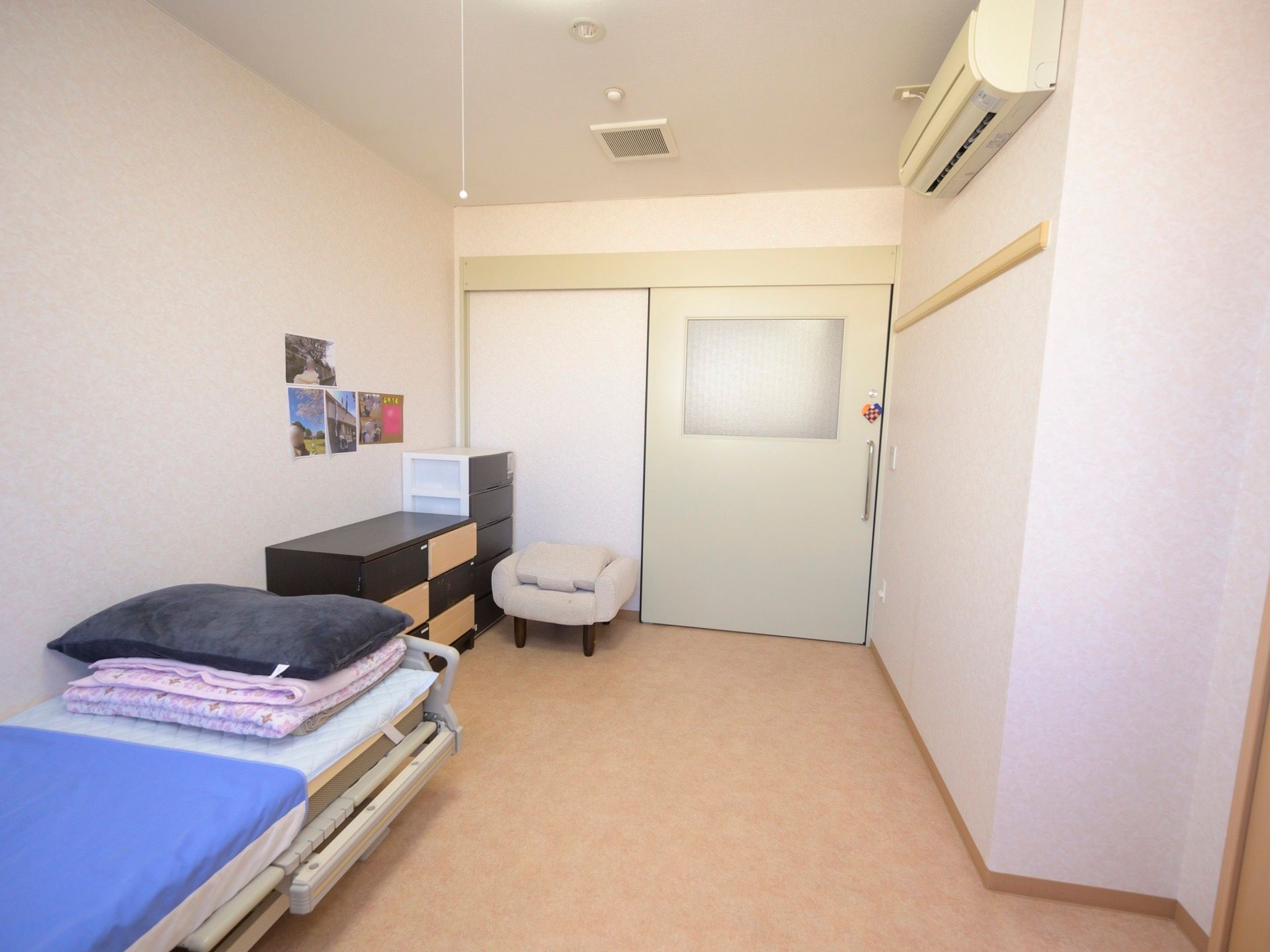 エアコンが完備されている居室で、ベッドや収納棚などが設けられている。スライド式の扉の取っ手部分には、装飾が施されている。
