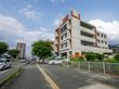 広い歩道の横に位置する４階建ての白い建物