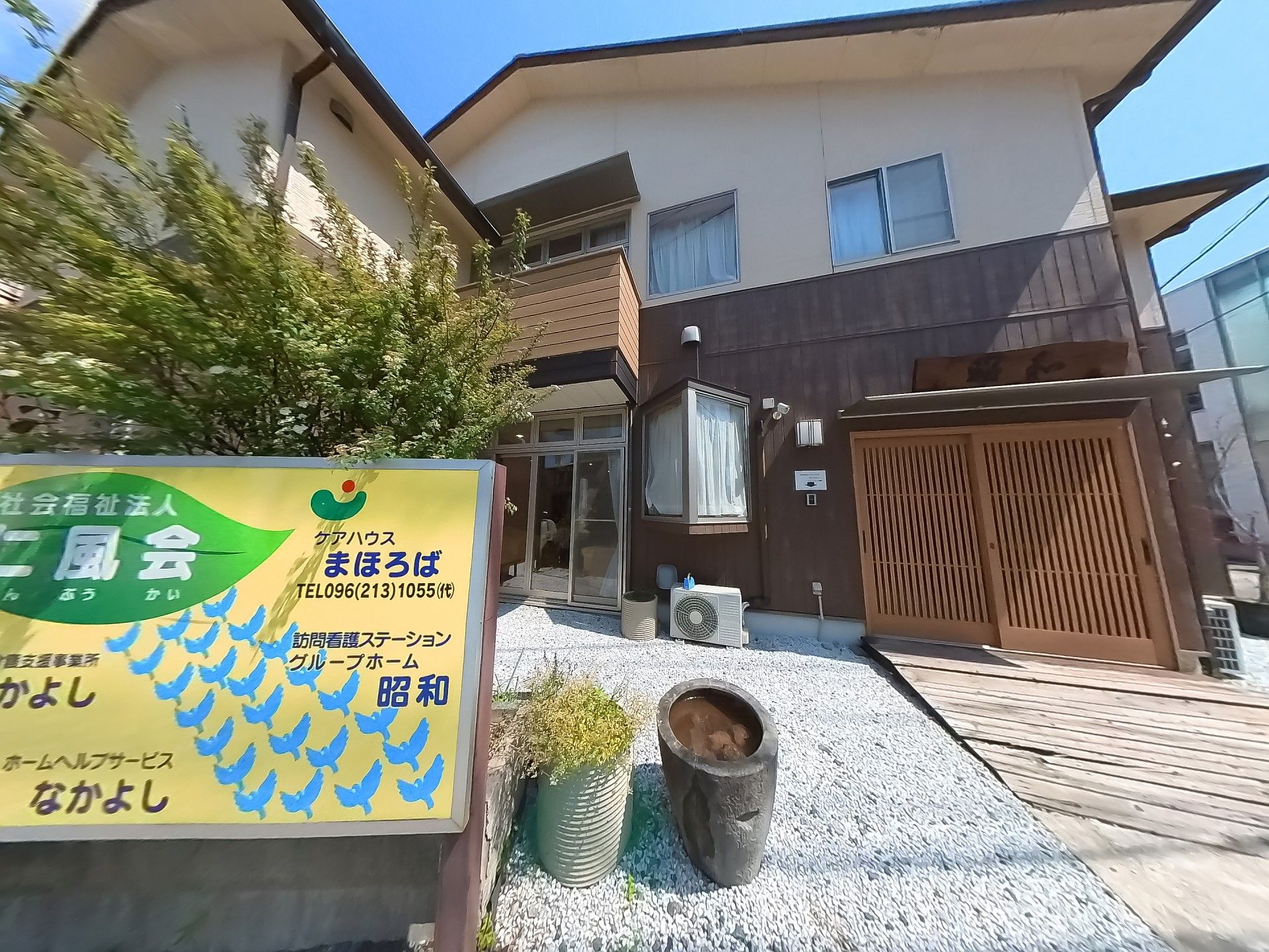 白とブラウンの２階建ての建物は日当たりのいい場所に建っている。玄関には大きな表札がある。