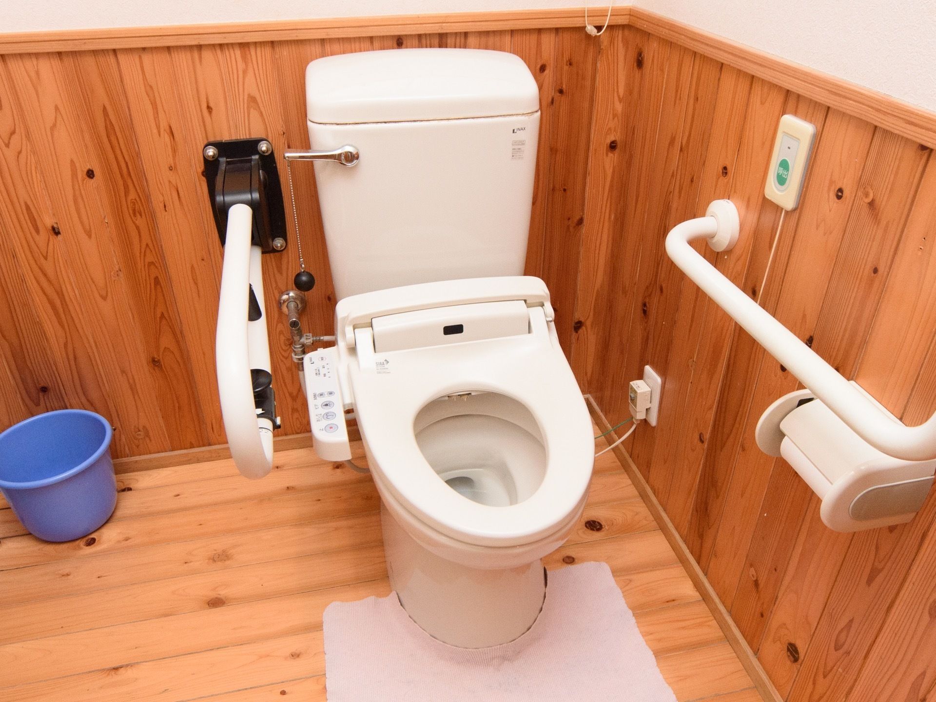 床面と腰高の位置まで木の板が貼られているトイレである。暖房洗浄機能つきの便座で、コードがコンセントにつながっている。