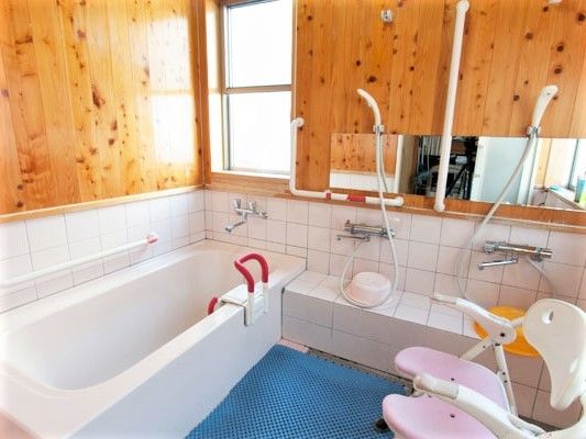 一人用の浴槽が設置された浴室。シャワーやシャワーチェアもあり、手すりが壁と浴槽についている。