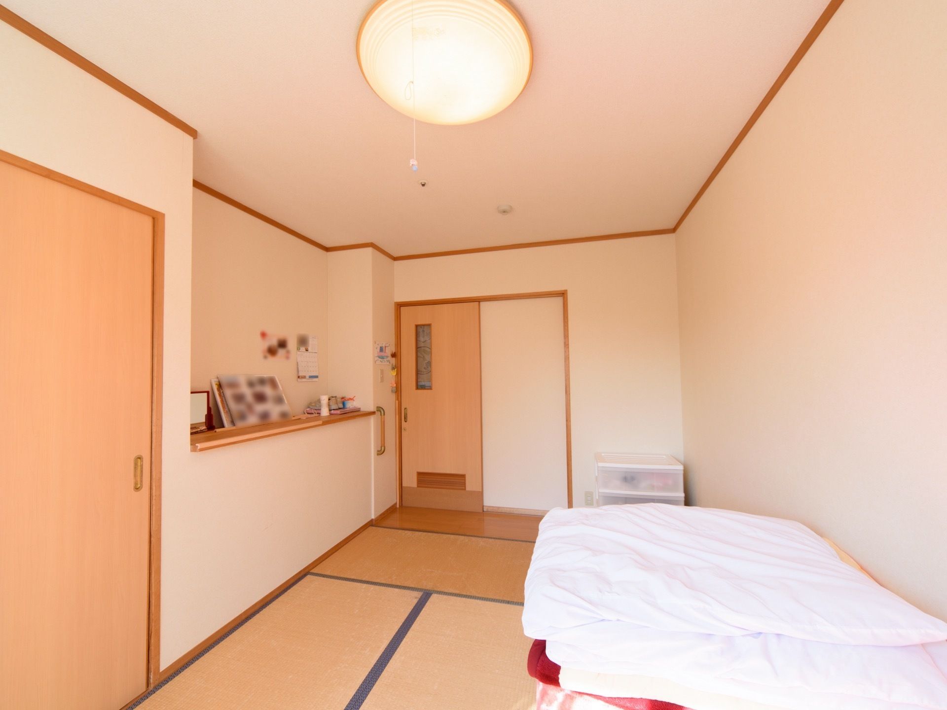 白を基調とした明るく清潔感のある居室。ベッドのほか、手すりや収納が取り付けられている。畳敷きで落ち着ける空間である。