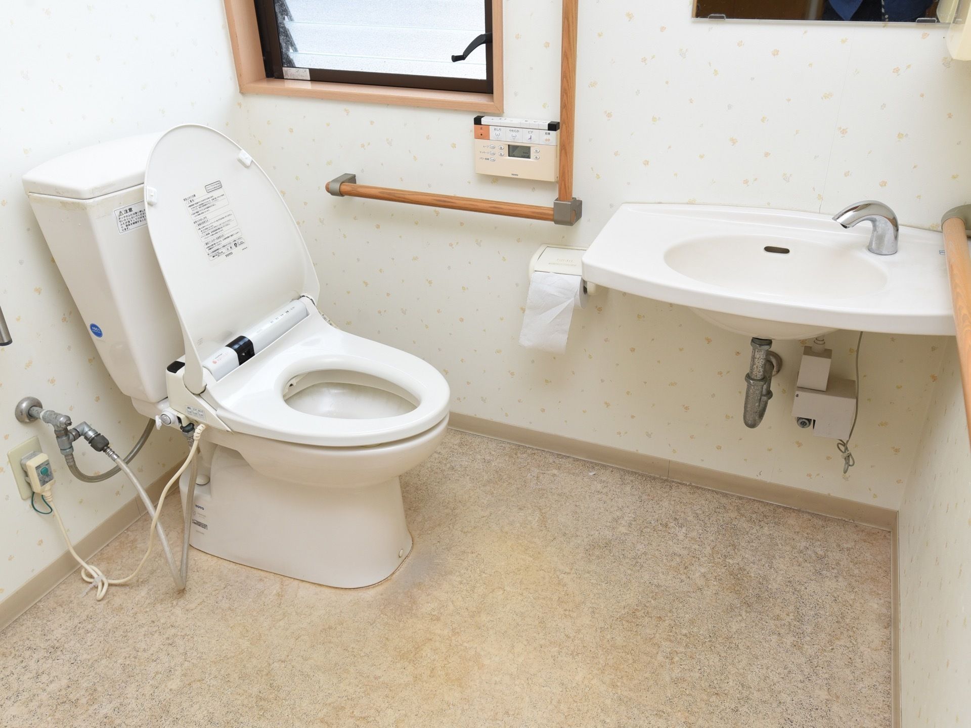 洗面台や温水洗浄便座が完備されたトイレである。Ｌ型や水平型手すりが壁に設置されており、換気に使用できる窓が設けられている。