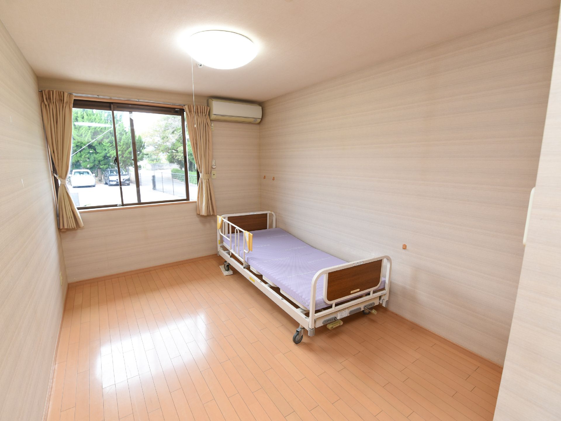 フローリングの部屋に介護用ベッドが置かれている入居前の居室