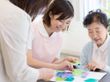 アジサイの貼り絵を楽しそうにしているエプロンを付けた若い女性スタッフと高齢女性。