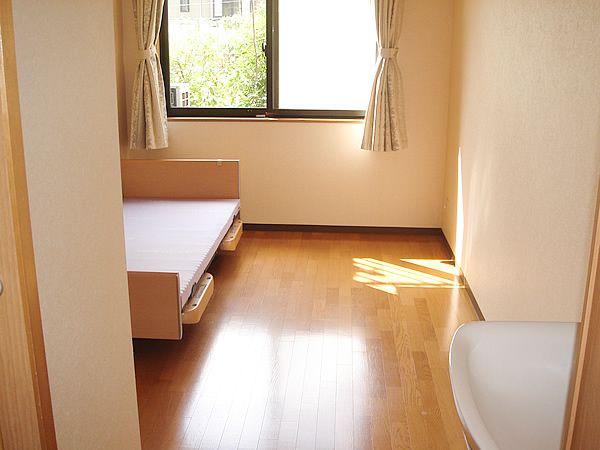 洗面所が設置されたフローリングの部屋には大きな窓があり、日当たり良好。介護ベッドも置かれている。