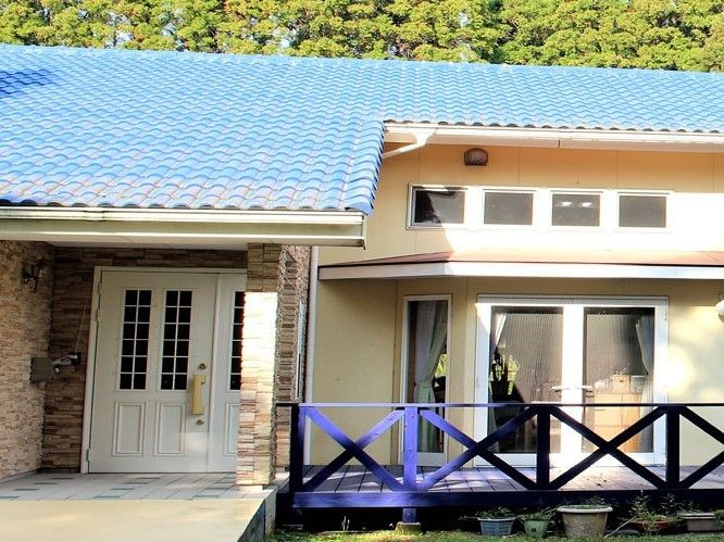 ウッドデッキ付きの平屋建ての建物はブルーの瓦屋根で家庭に近い雰囲気。