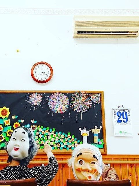 エプロンを付けた若い女性スタッフが車いすの高齢女性が指さす方向を一緒に笑顔で見ている。