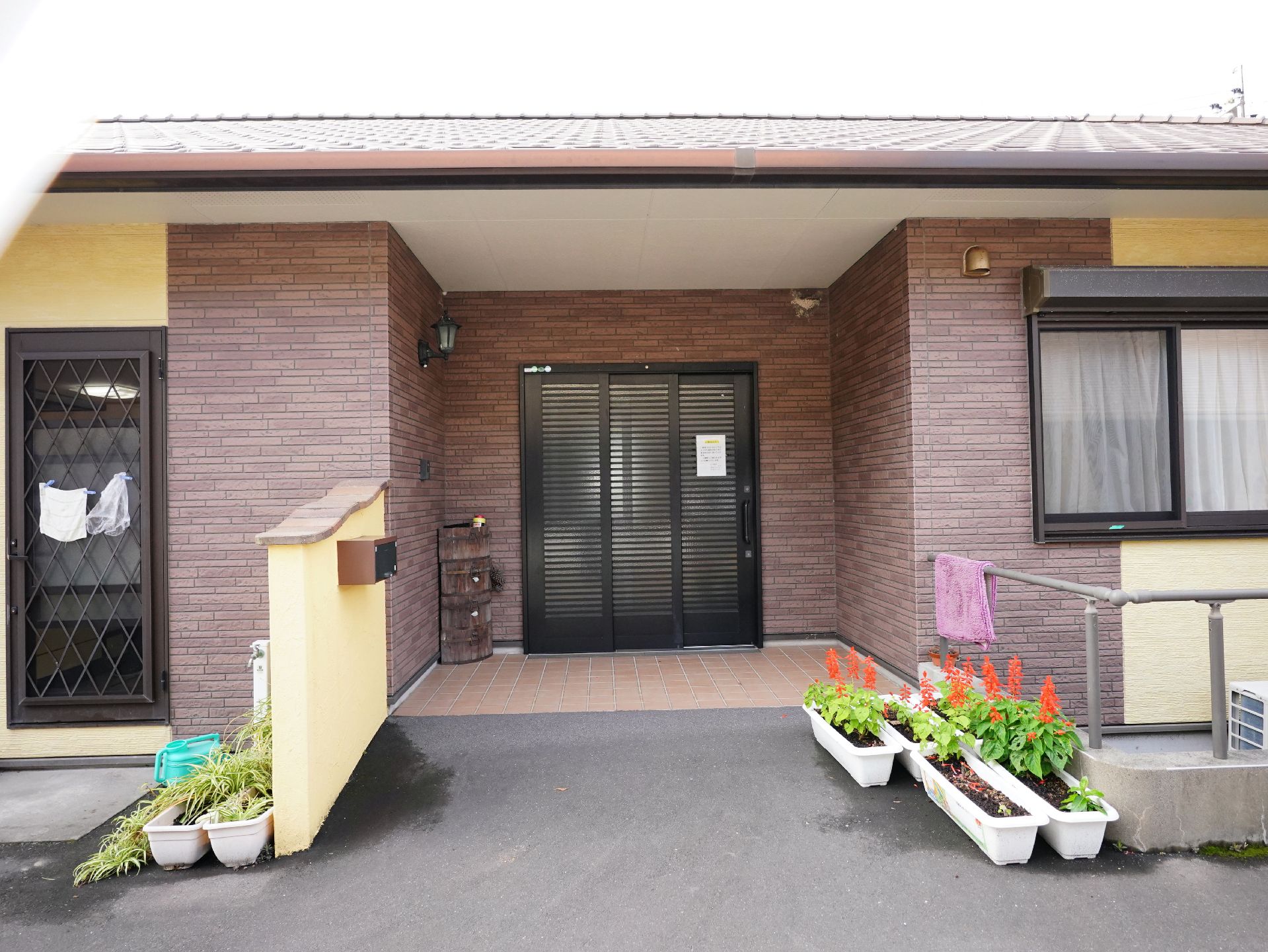 高齢女性と付き添いの高齢男性、そして若い男女のスタッフが屋外で笑顔で過ごしている様子。