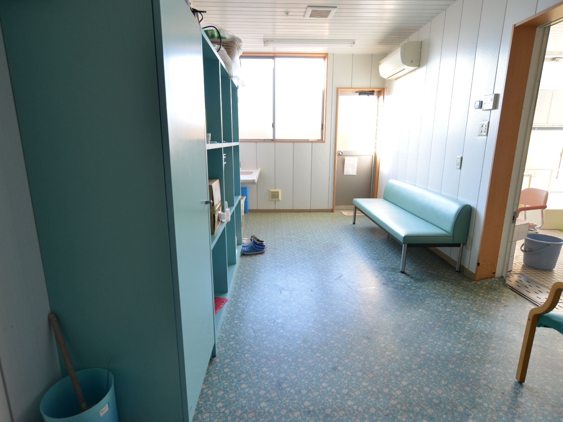 浴室前の脱衣所は広々としていて、棚や長椅子、エアコンなどの家具や設備が整っている。奥には、洗面台も設置されている。