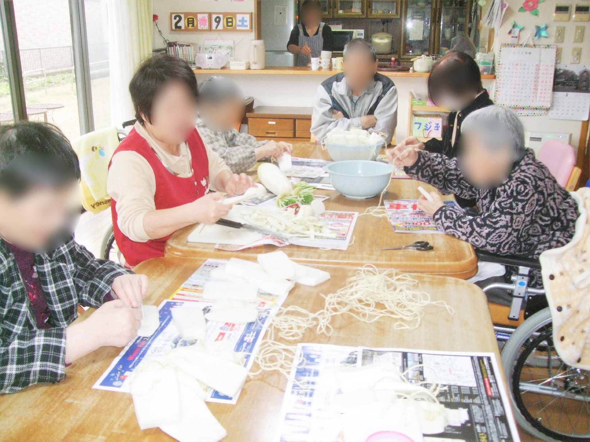 医師・看護師に囲まれて笑顔で写真に納まる女性。車いすに乗っている様子