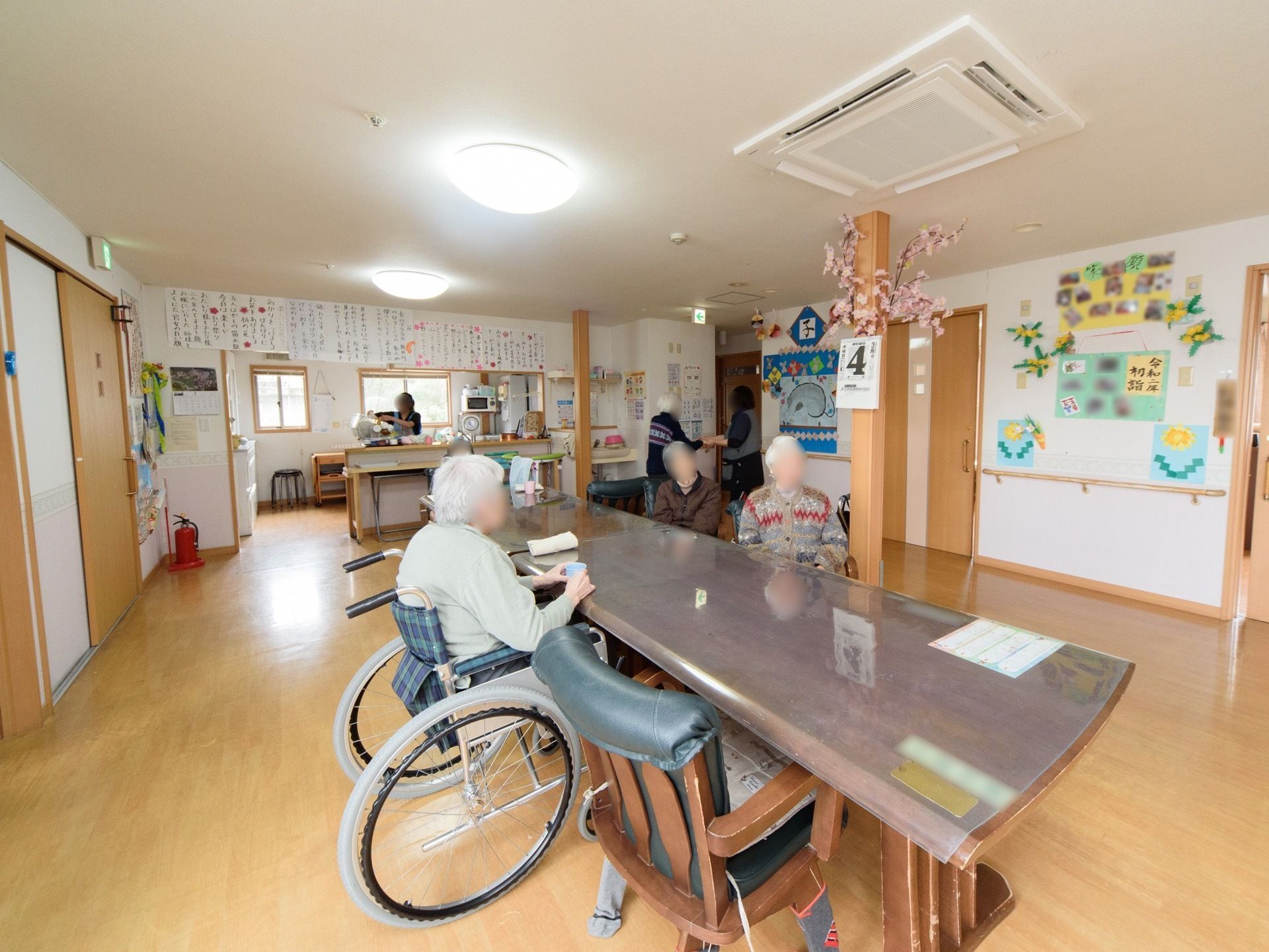 フローリングの広々とした空間に、テーブルセットが置かれている。入居者が席について、くつろいでいる。