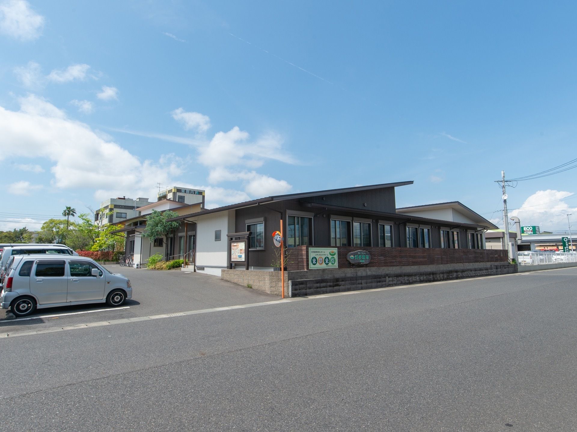 大きな道路に面しているグループホームで、周辺には高い建物がなく見晴らしが良い。敷地内に駐車場が完備されている。