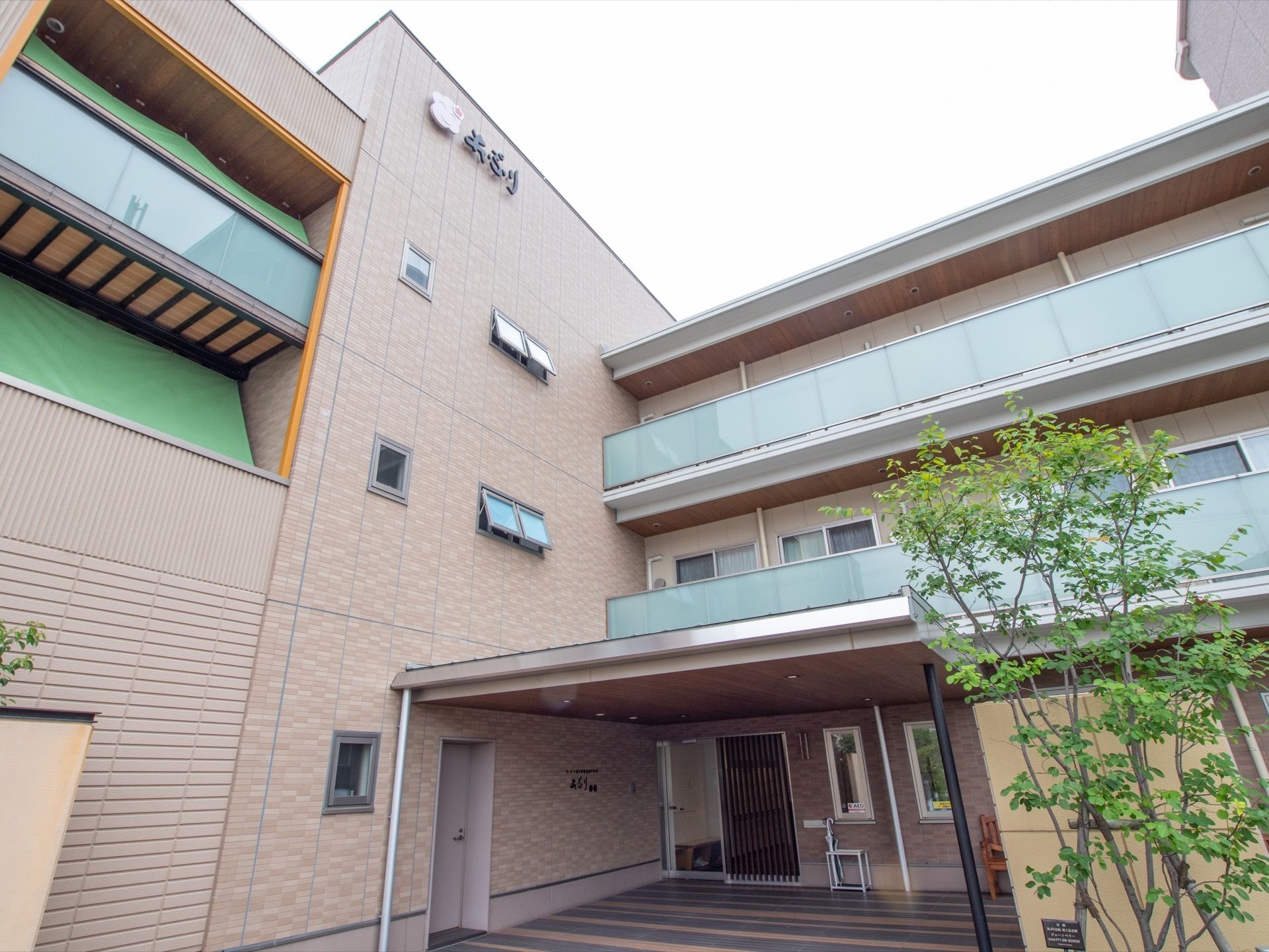 ３階建ての建物で、茶色系で統一された落ち着いた佇まいである。玄関ポーチには屋根があり、入り口前に植物が植えられている。