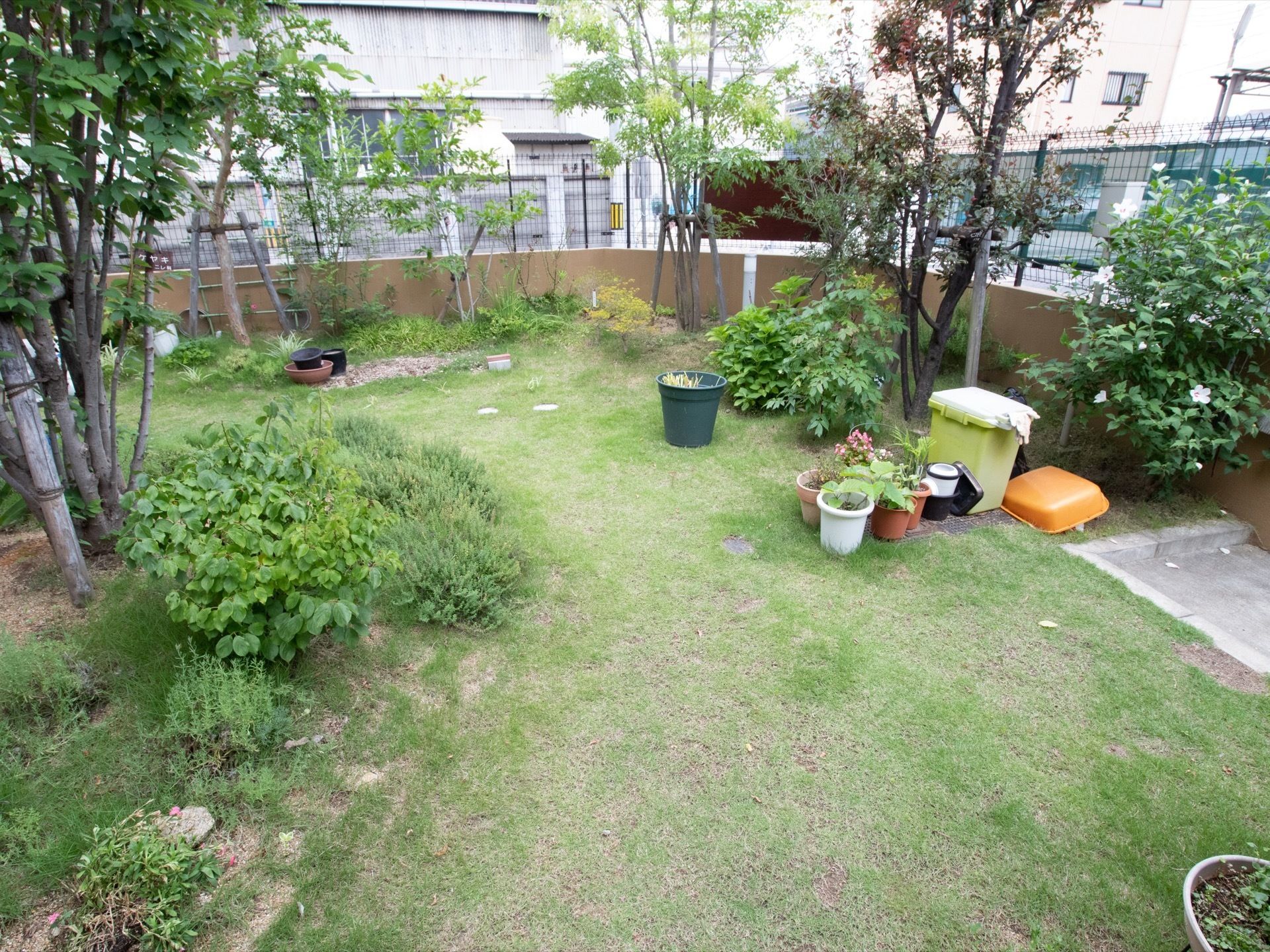 施設敷地内に広い中庭がある。大きく育った樹木や低木、鉢植えなどが育てられている。ゴミ箱が置かれている。