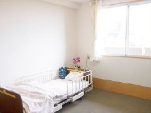 壁際に布団が敷かれた介護用ベッドが置かれている個室