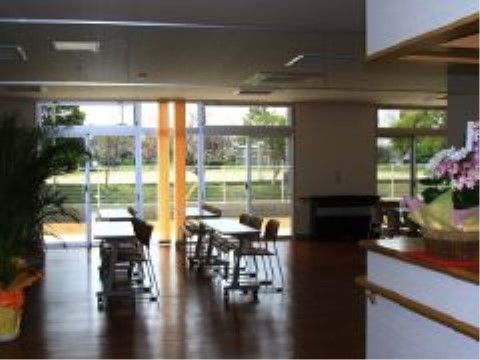 大きな窓があり、開放的な空間である。長机と椅子が並べられており、入居者様や地域の方々が利用できるようになっている。