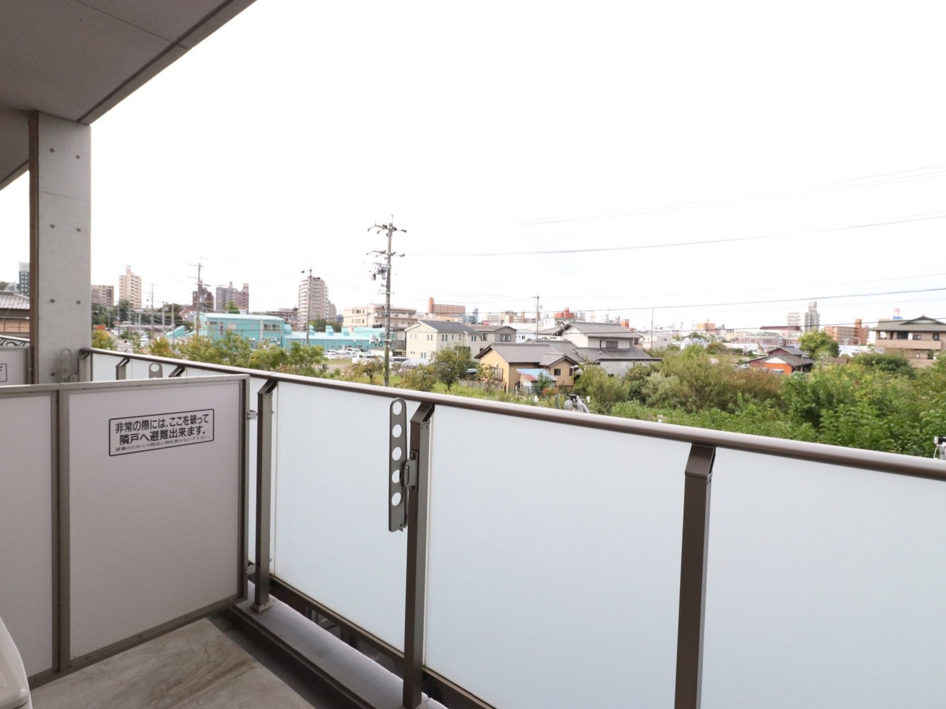 居室から眺めることのできる街並み。施設周辺の木々や、住宅、マンションなどの建物が見渡せる。物干しざおが使えるようになっている。