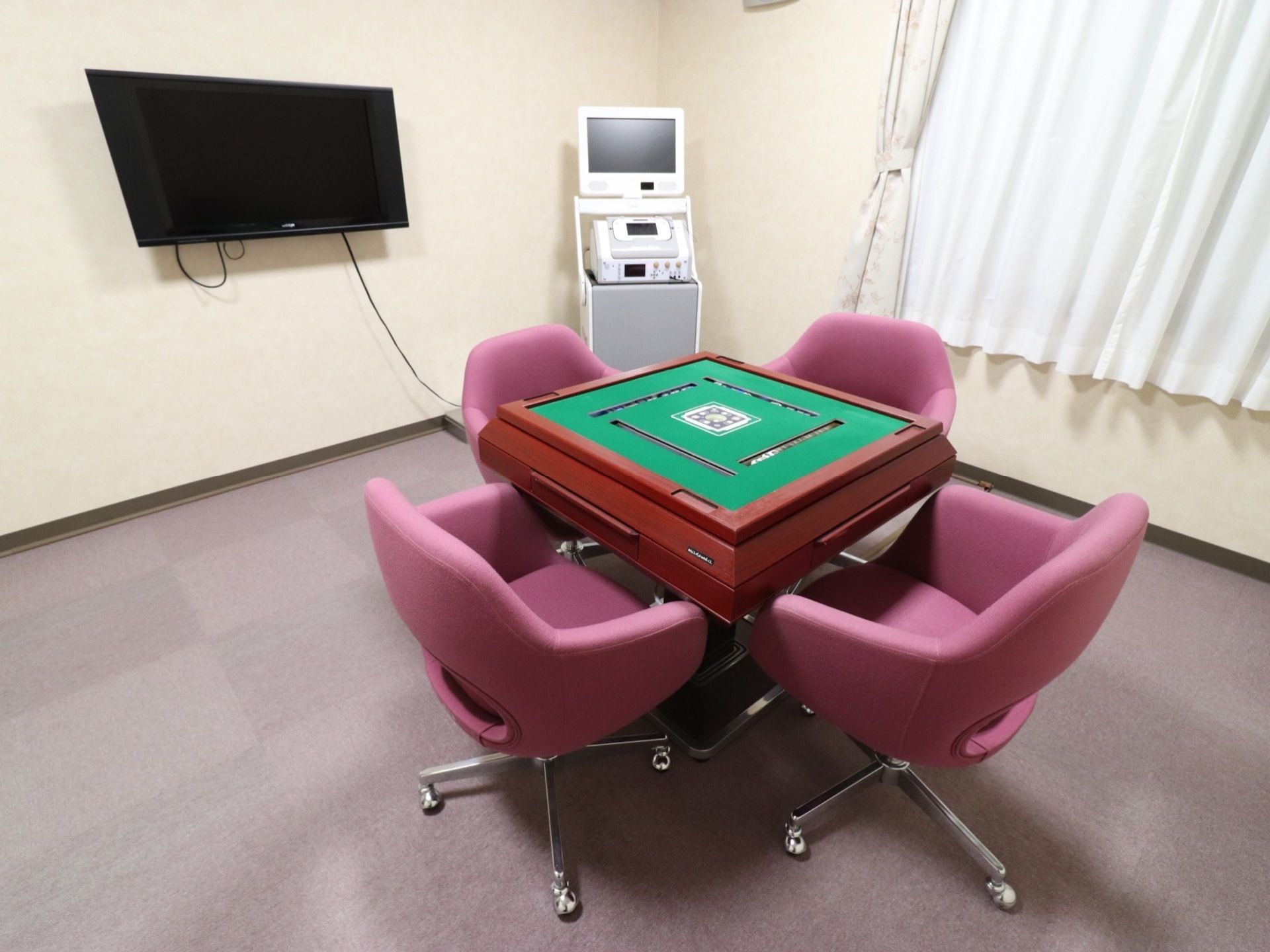 真ん中に自動で麻雀パイを並べる専用の台が置かれている。奥にはカラオケができる機材があり、モニターにつながれている。