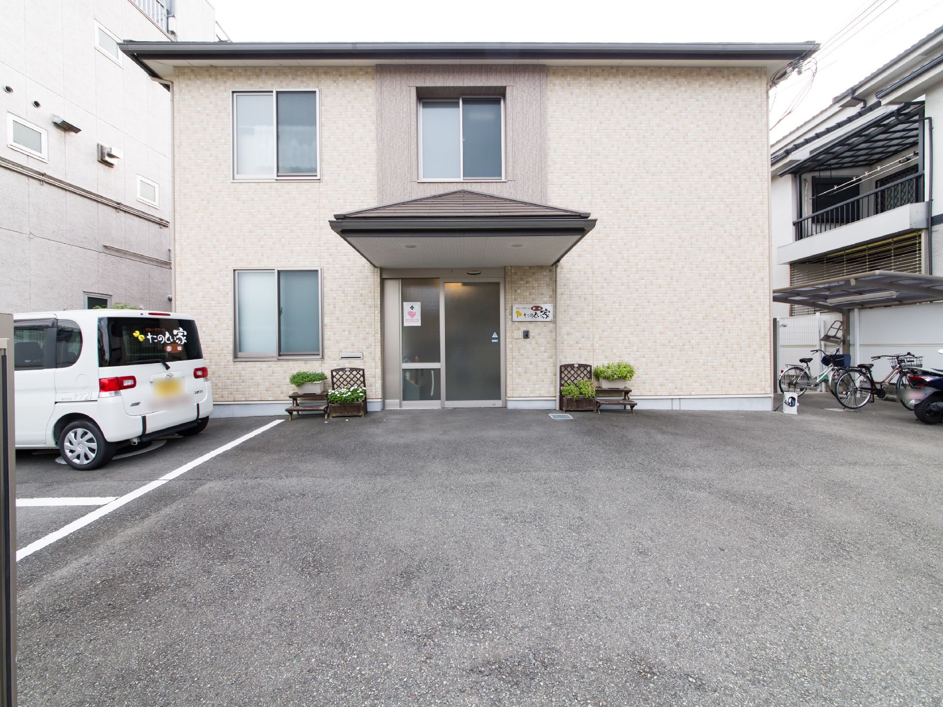 施設を正面から見たところ。自動ドアの左右は鉢植えで飾られている。また建物の右側には正門を向いた窓がない。