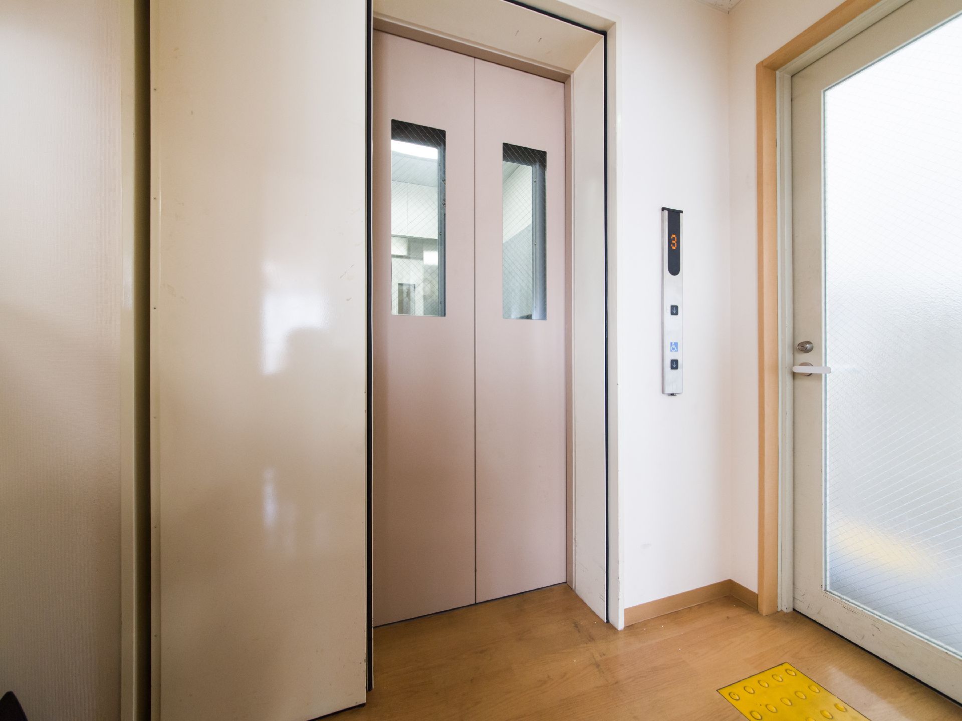 エレベーターがあり、壁に操作パネルが取り付けてある。階下へ行くボタンが取り付けてある。車椅子用ボタンがあり、扉の開閉時間が少し長めにできる。