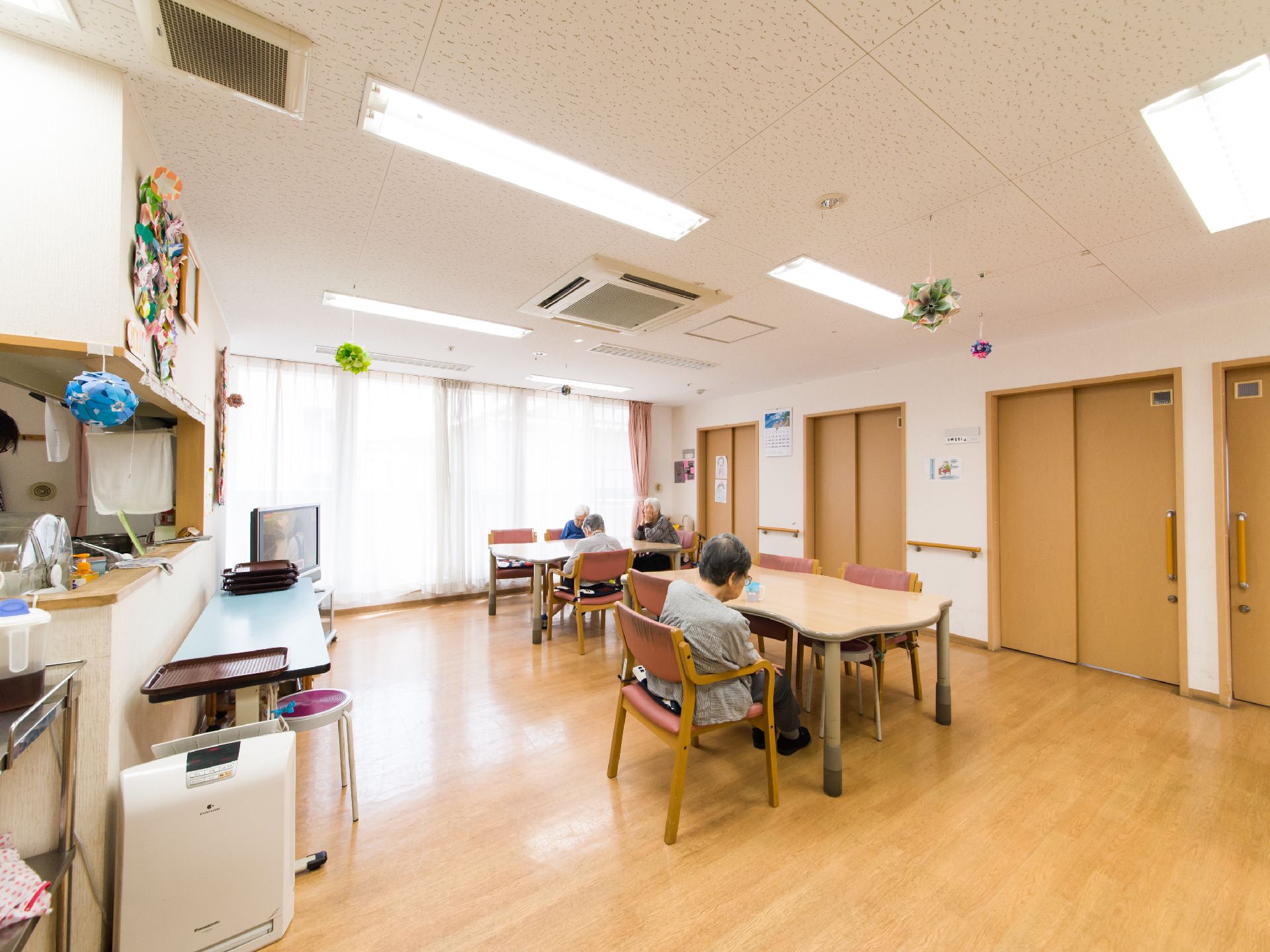 キッチンから食堂が見渡せる。入居者が四名ほど椅子に座っているのが見える。テレビがあり、共有で鑑賞できる。