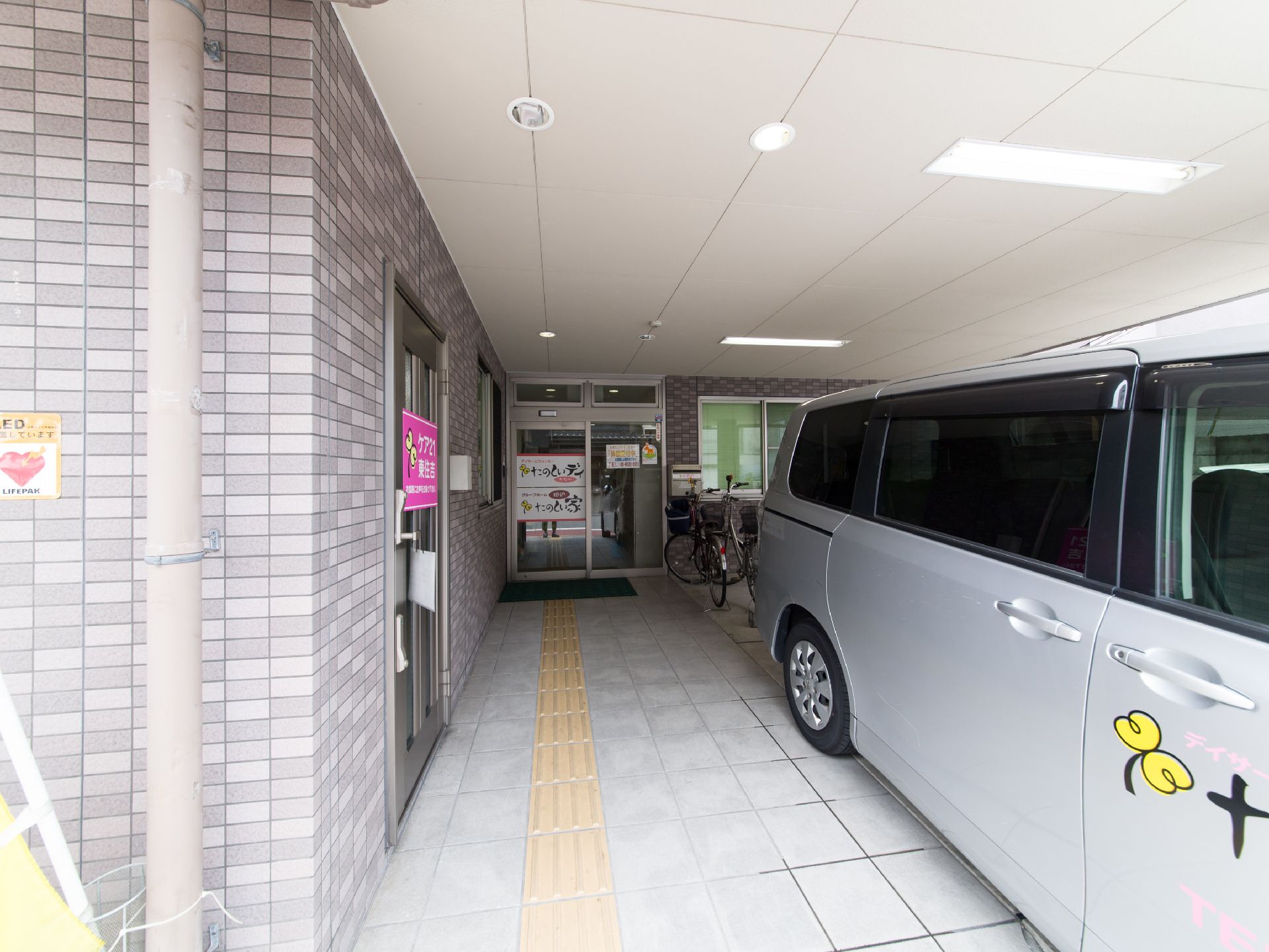玄関前には自動車と自転車が置けるスペースがある。車の横は車椅子でも通れる広さがあり、入口も自動ドアになっている。