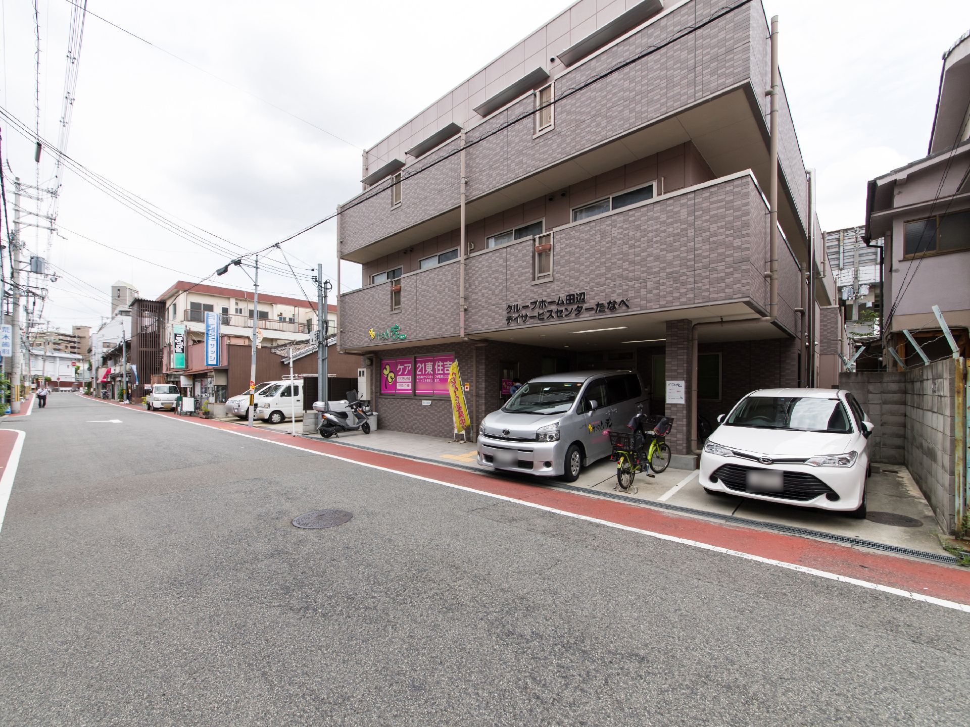 施設の周囲は、住宅街で近くにJR駅、地下鉄駅などがある。建物の前面に駐車場がある。三階建ての施設である。