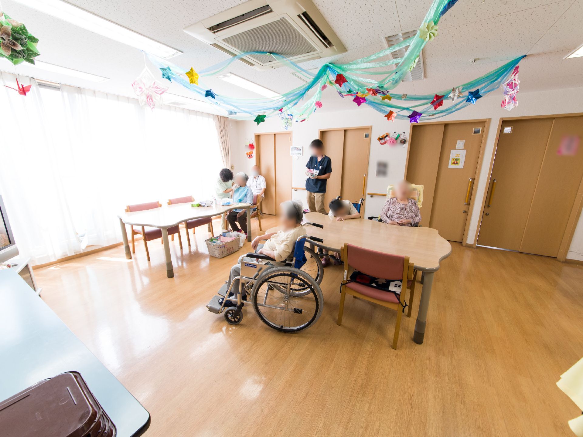 居室の戸を開けると多目的室/食堂につながっている。スタッフによって、歯磨きを手伝ってもらっている入居者がいる。