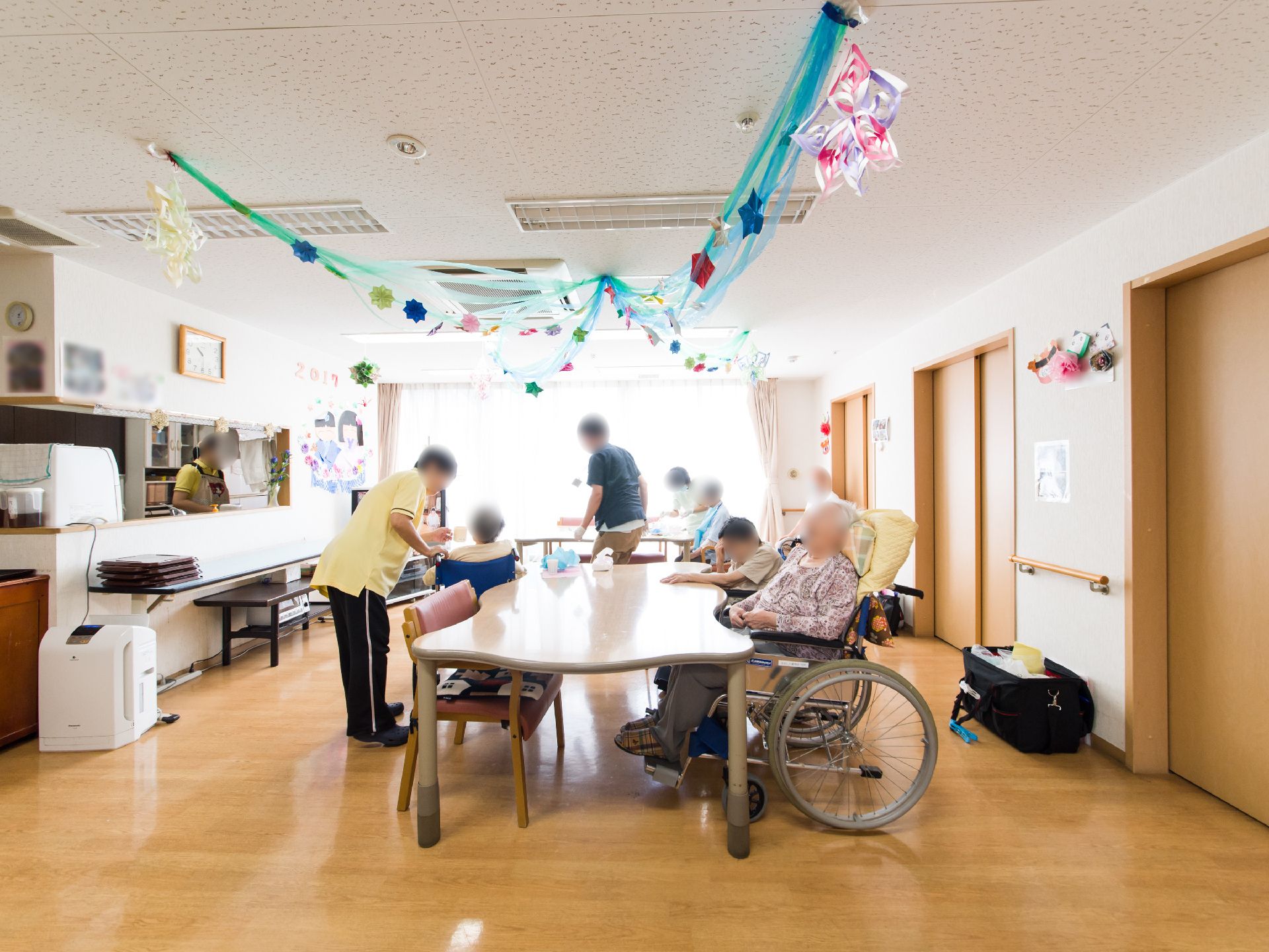 大きなテーブルの周りで椅子に座ってスタッフと話している入居者様